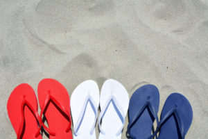 Red white and Blue flip flops on the sand