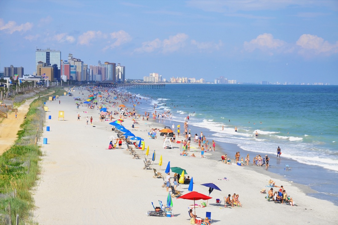 View down Myrtle Beach South Carolina with beach goers using brightly colored umbrellas