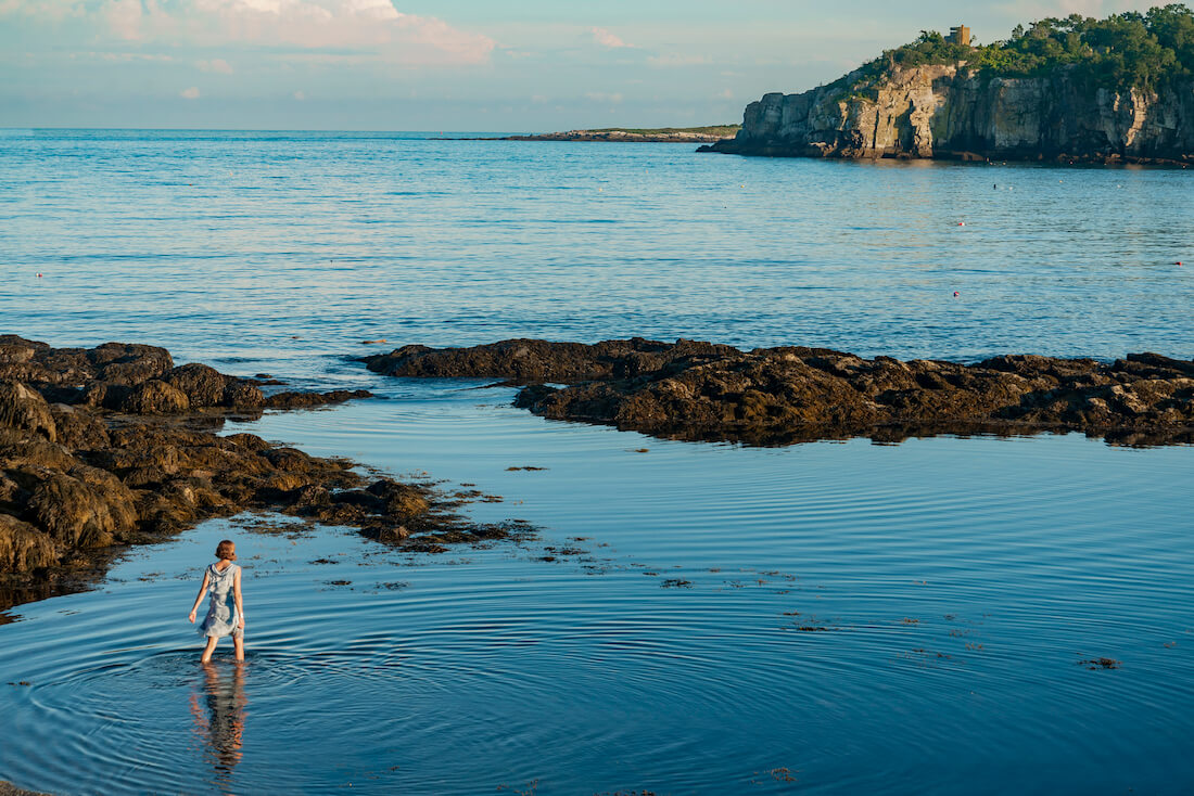 A woman walks in the shallow waters of Peak Island in Maine