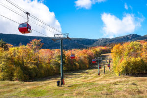 Red enclosed gondolas overhead against a blue sky in autumn in Vermont