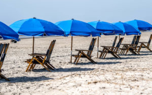 Beach chairs lined up with blue umbrellas in Hilton Head South Carolina