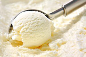 Vanilla ice cream scoop, scooped out of container with utensil