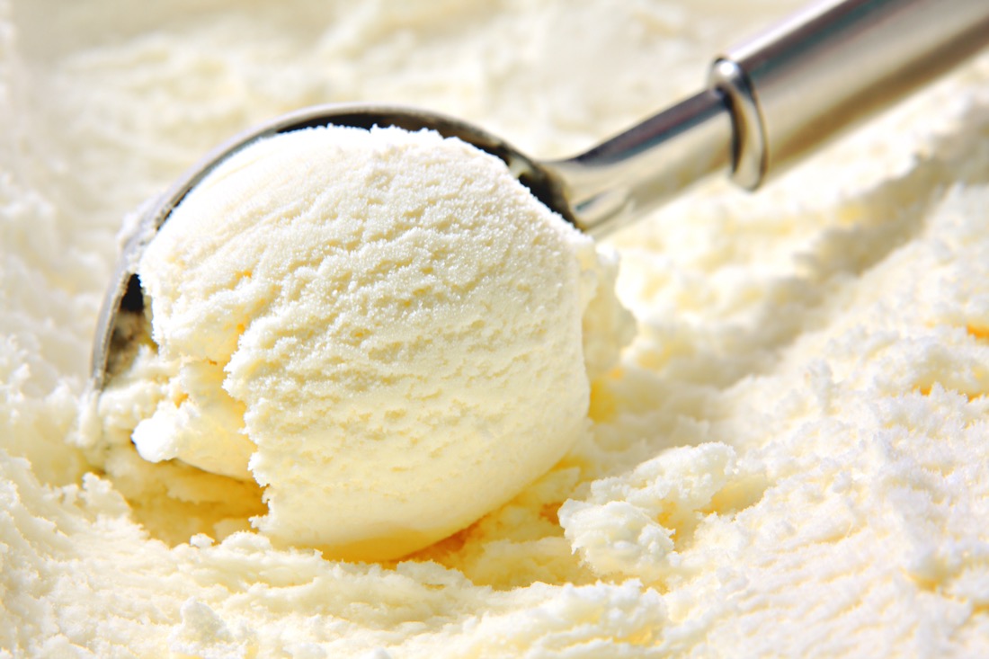 Vanilla ice cream scoop, scooped out of container with utensil 
