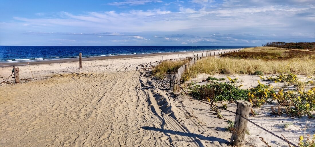 View of Duxbury Beach in Massachusetts with a fence lining the sandy path to the shore