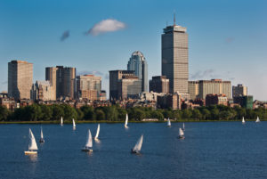 View of the Boston skyline from the Charles River Esplanade with multiple sailboats on the water in between