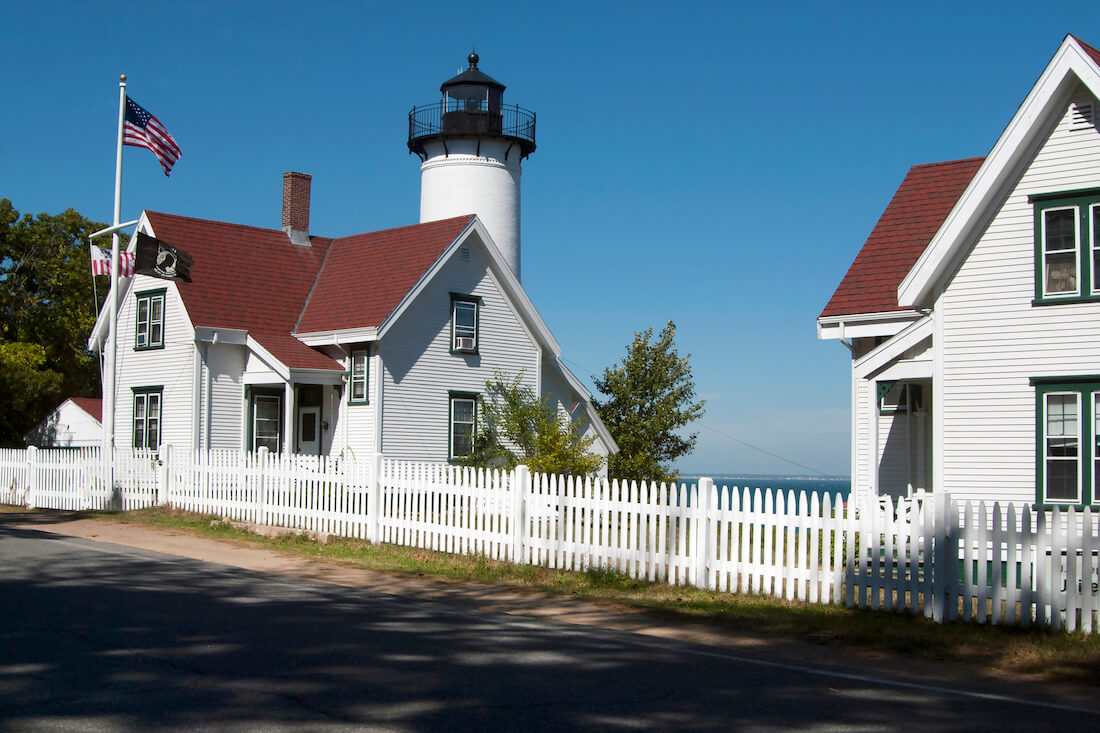 White wooden home with a US flag out front at the Keeper's Buildings at West Chop Lighthouse on Martha's Vineyard, MA