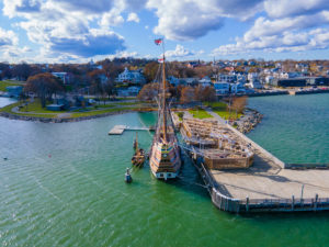 Aerial view of the Mayflower II in Plymouth Harbor, with the town of Plymouth leading up from the shore beyond it
