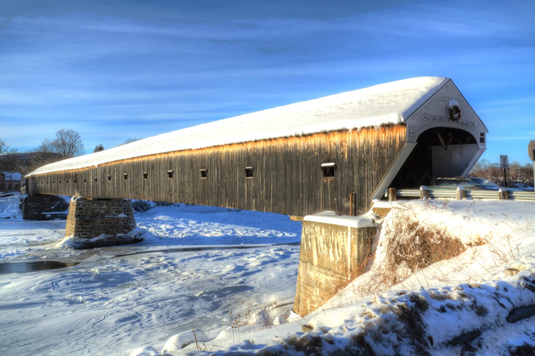 A snow covered Cornish-Windsor Two Lane Covered Bridge Spanning the Connecticut River