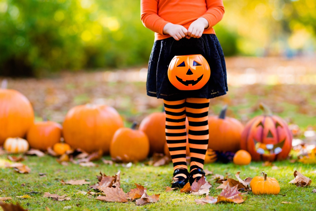 Fall scene with kid holding trick or treat bowl in pumpkin patch