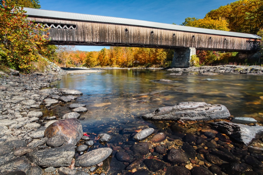 West Dummerston Covered Bridge over river with fall color trees
