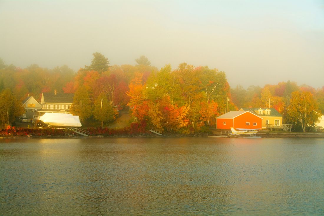 Views of the lake with autumn colors in a foggy morning at Greenville, Maine