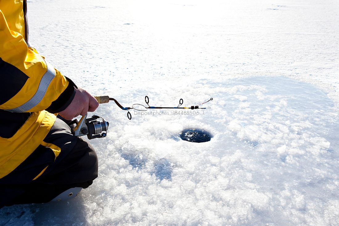 Man doing ice fishing in a frozen lake in winter