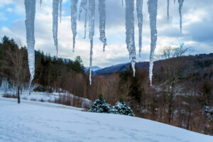 Ice stalactites frame a cold morning scene in winter in Killington Vermont