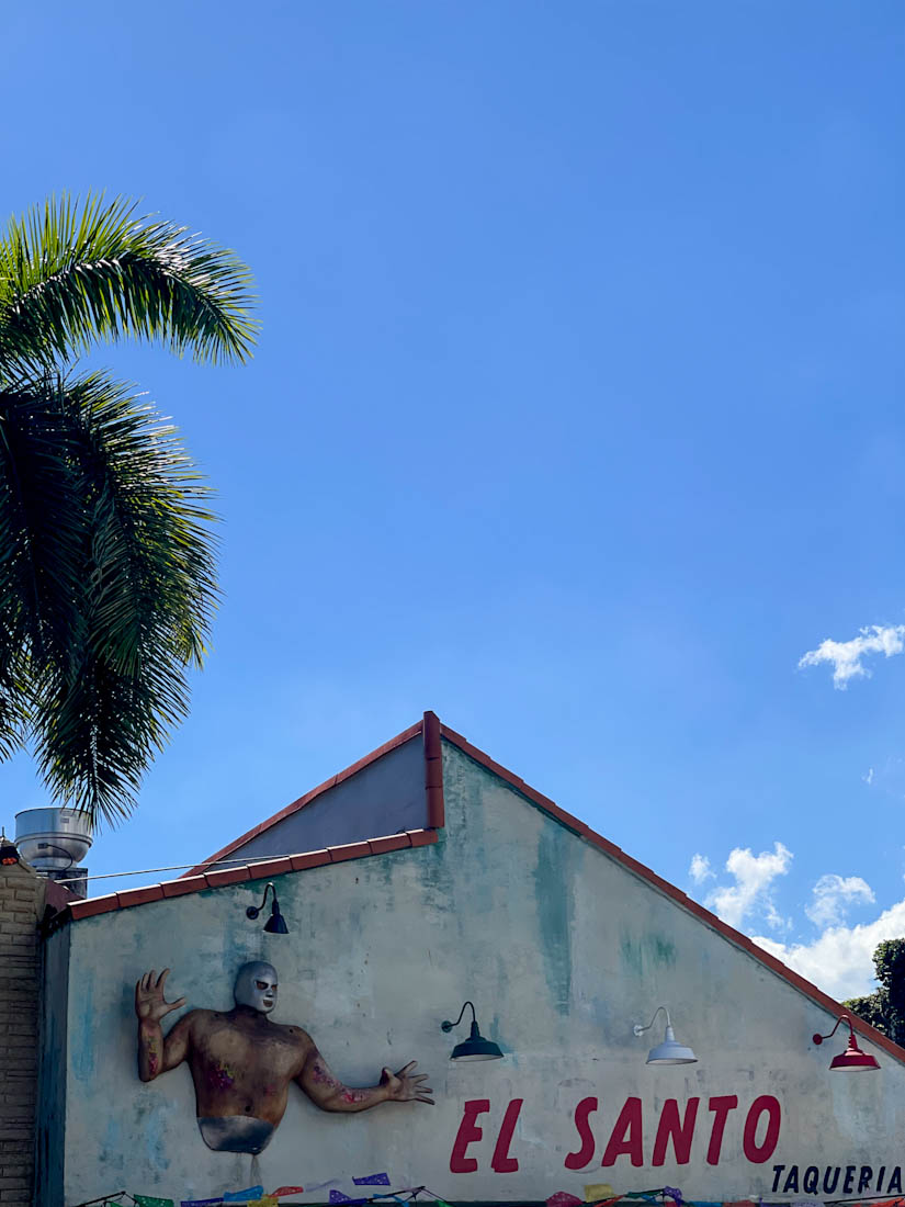 Sign for El Santo Taqueria with blue skies and palm tree on Little Havana Miami
