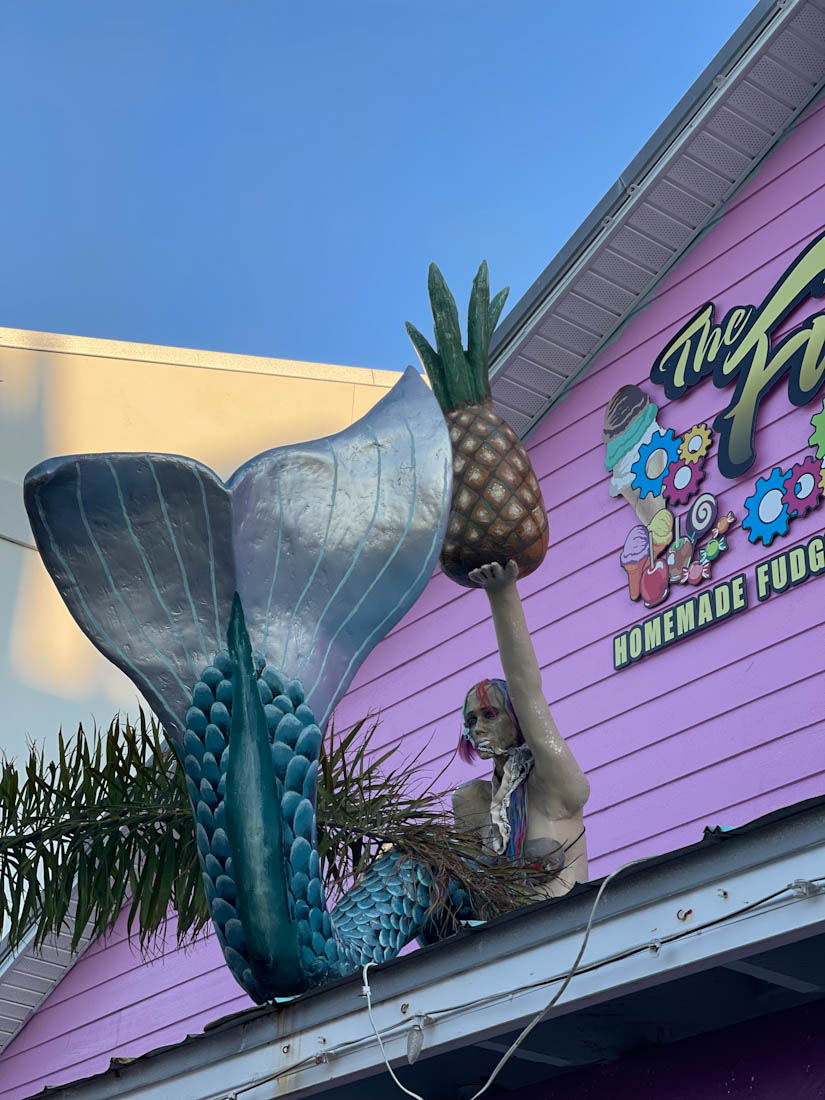 Close up on sign of Fudge Factory in Anna Maria Island with a mermaid statue, Florida