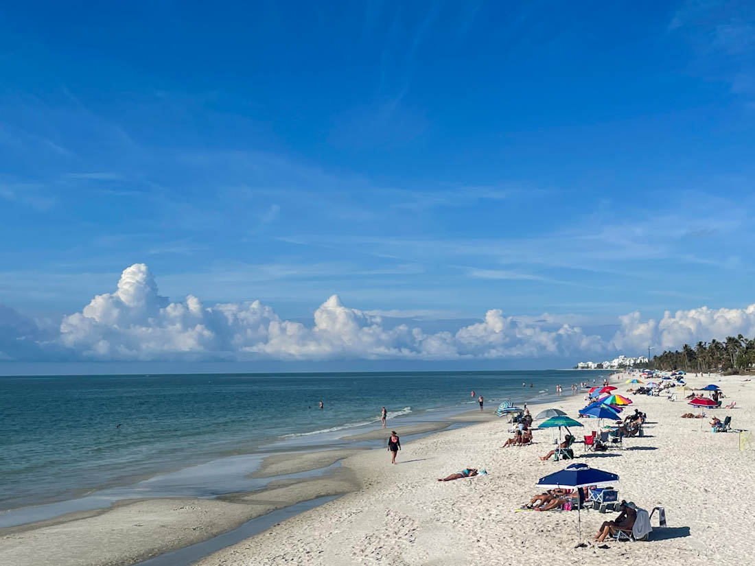 Naples beach with sunbathers and umbrellas by the ocean in Florida