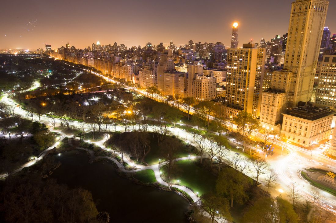 Aerial view of Central Park and nearby buildings with lights in NYC at night.