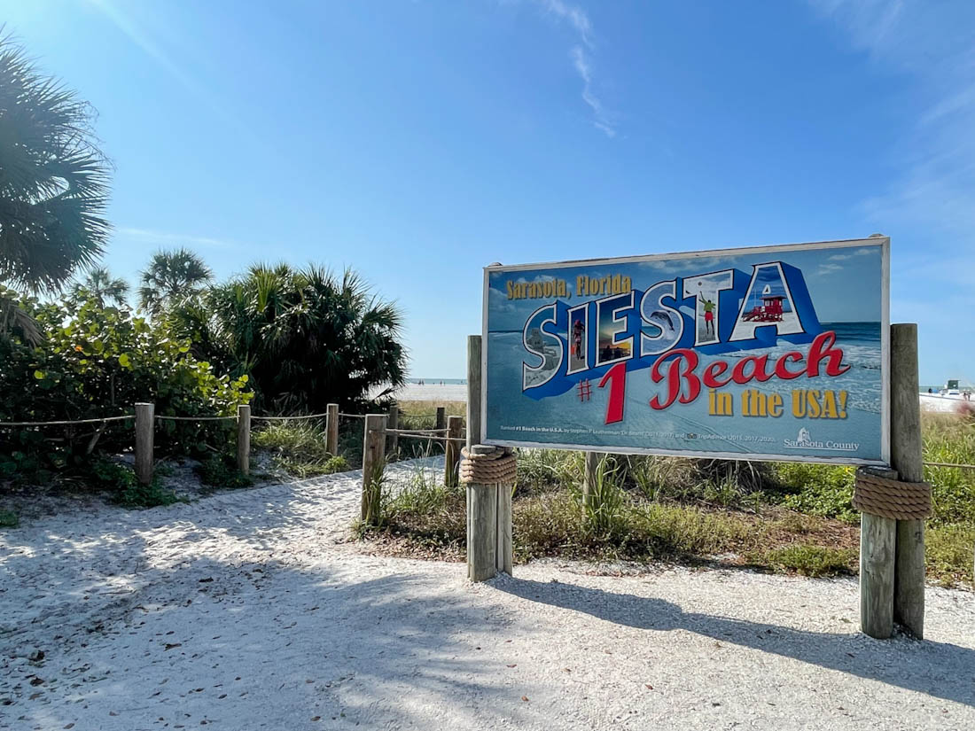 Siesta Key Beach sign leading to sandy path in Florida 