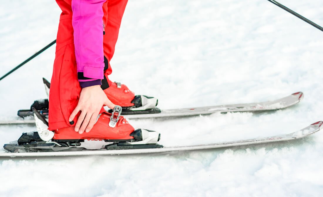 Close up of a skiier fixing a boot