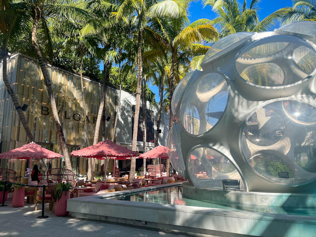 Buckminster Fly Eye Dome surrounded by palm trees and a pink cafe at Palm Court Design District Miami 