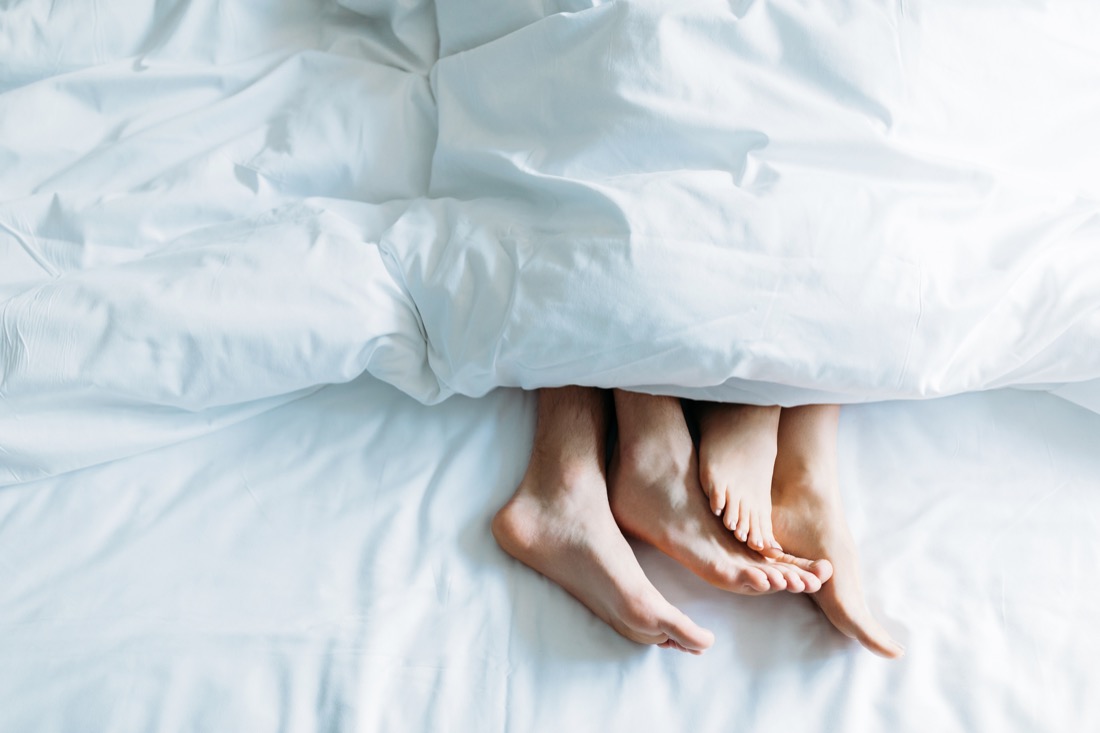 Couple in bed, feet on show at bottom of duvet