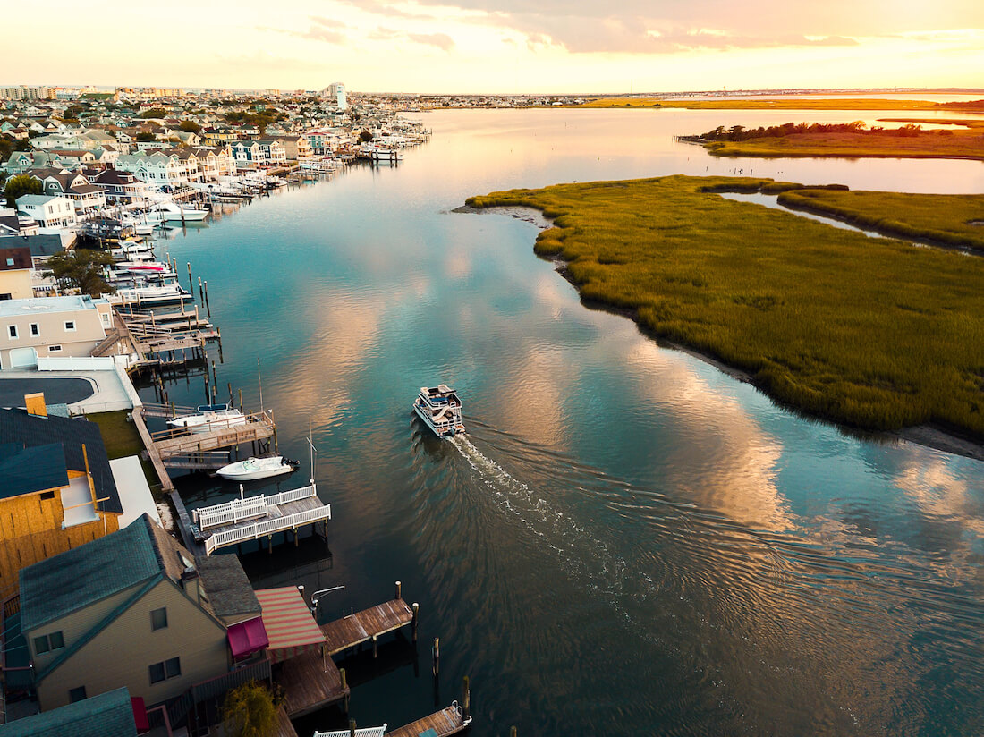 Aerial photo of a boat sailing in still water of the bay at sunset in Wildwood New Jersey