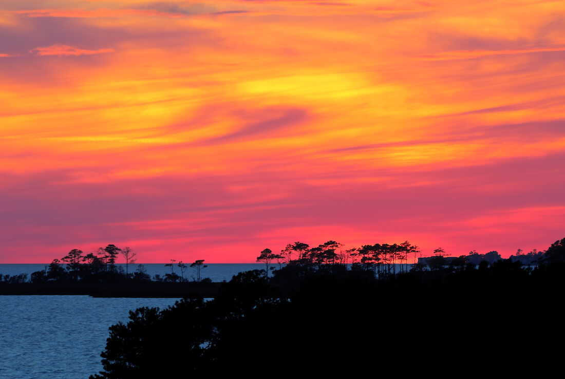 A dramatic, colorful sunset over Albemarle Sound viewed from Jockeys Ridge State Park in the town of Nags Head on the Outer Banks of North Carolina