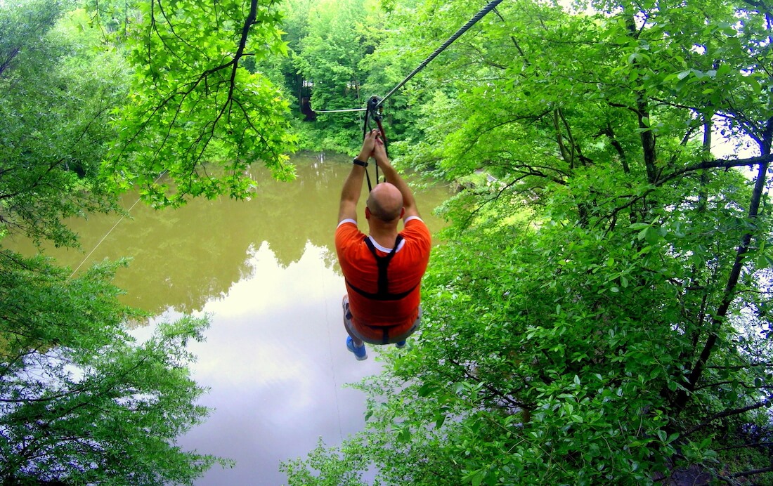 A man ziplining across a river in the summer near Lums Pond State Park, Delaware